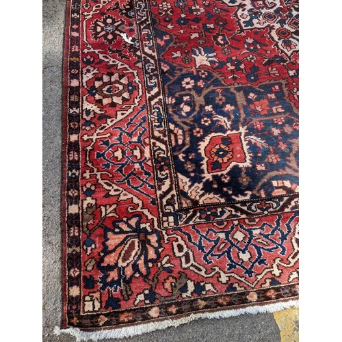 490 - An Iranian hand woven carpet having a red ground, geometric motifs and tasselled ends, 372cm x 300cm... 