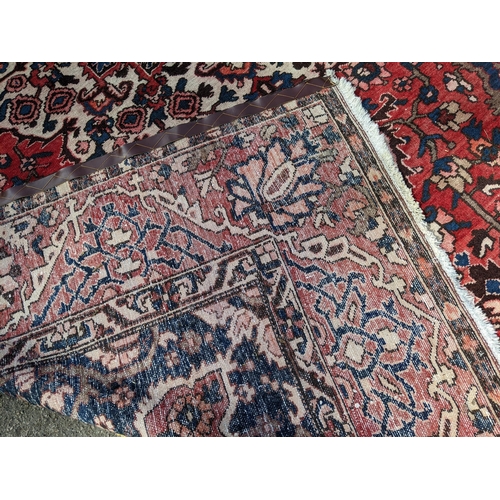 490 - An Iranian hand woven carpet having a red ground, geometric motifs and tasselled ends, 372cm x 300cm... 