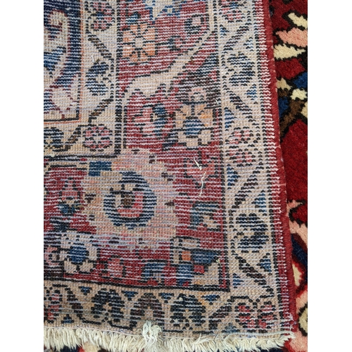 497 - A Persian Bakhtiar hand woven rug having a red ground with a central motif and multiguard borders, 2... 