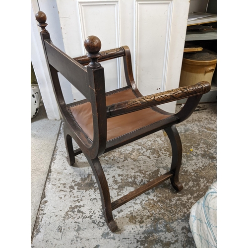 445 - A late Victorian Savonarola oak carved armchair having leather seat turned finials and a carved X fr... 