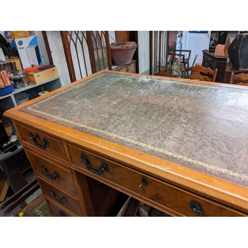 494 - A reproduction yew twin pedestal desk having a leather topped scriber and nine drawers, 77cm h x 122... 