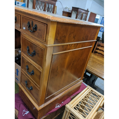 494 - A reproduction yew twin pedestal desk having a leather topped scriber and nine drawers, 77cm h x 122... 