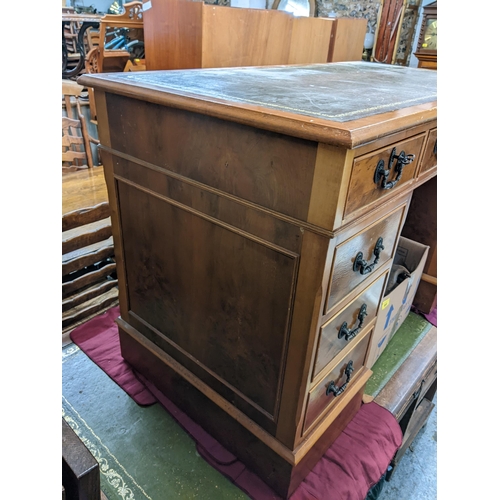 494 - A reproduction yew twin pedestal desk having a leather topped scriber and nine drawers, 77cm h x 122... 