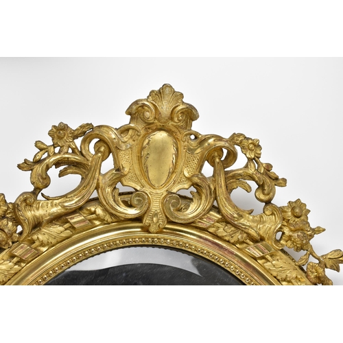 168 - A large 19th century carved and giltwood oval mirror, with pierced acanthus and floral crest, beaded... 