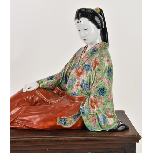 83 - A Japanese kutani porcelain model of a geisha, early 20th century, raised on a wooden stand, the fig... 