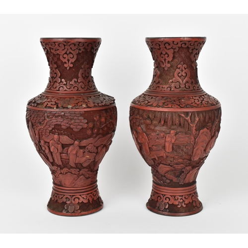 29 - A pair of Chinese red cinnabar lacquer vases, of baluster shape with carved continuous scene of elde... 