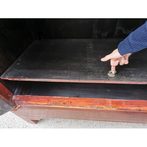 63 - A large Chinese red lacquer wedding cabinet, with moon lock to the central doors enclosing two drawe... 