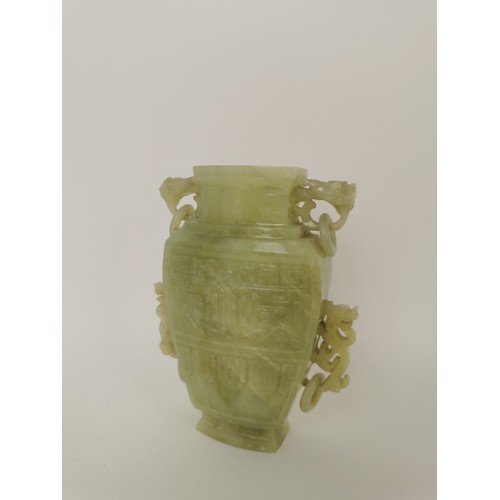 73 - A Chinese celadon jade taotie vase, of tapered form with dragon handles and hanging hoops, the front... 