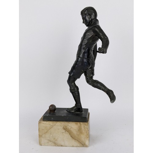 82 - An early mid 20th century patinated spelter football trophy fashioned as a footballer about to strik... 