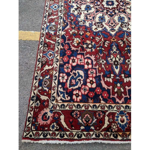 243 - A Persian Bakhtiar hand woven rug having a red ground with a central motif and multiguard borders, 2... 