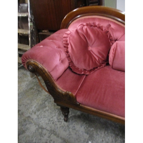 250 - A Victorian mahogany chaise longue upholstered in a pink dralon on turned legs and castors (one leg ... 