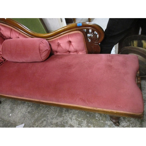 250 - A Victorian mahogany chaise longue upholstered in a pink dralon on turned legs and castors (one leg ... 