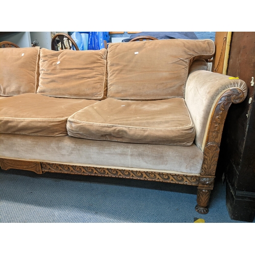 276 - An early 20th century three-seater sofa having an oak carved frame decorated with acanthus leaves an... 