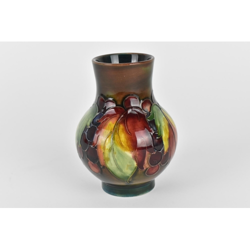 13 - A William Moorcroft pottery baluster vase, in the 'leaf and berry' pattern, the tubelined red/orange... 