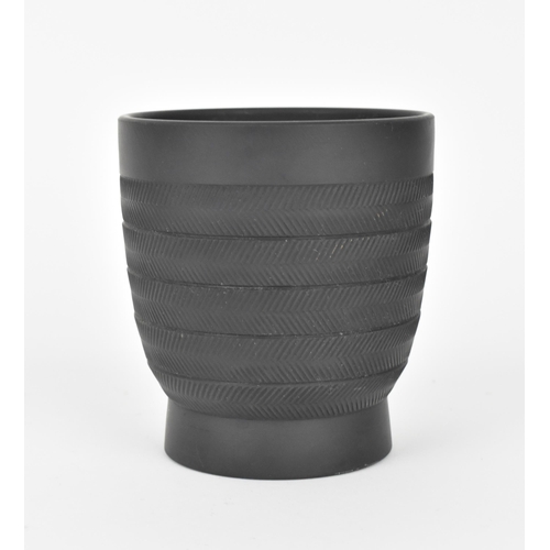 93 - A Keith Murray for Wedgwood black basalt vase, with textured striated frieze design, on a circular b... 