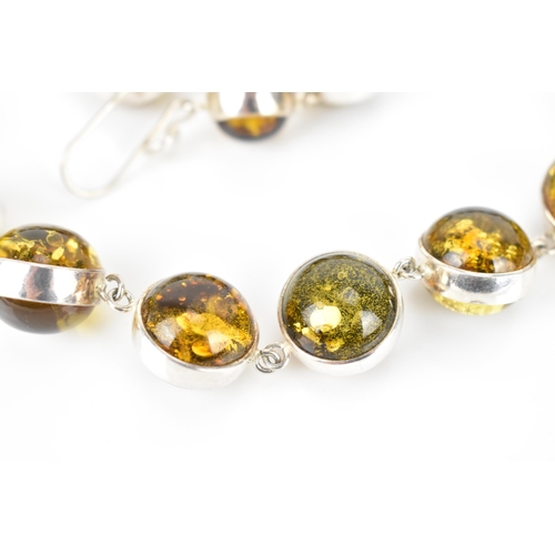 155 - A silver and green amber bead necklace with matching earrings, the amber beads with silver surround,... 