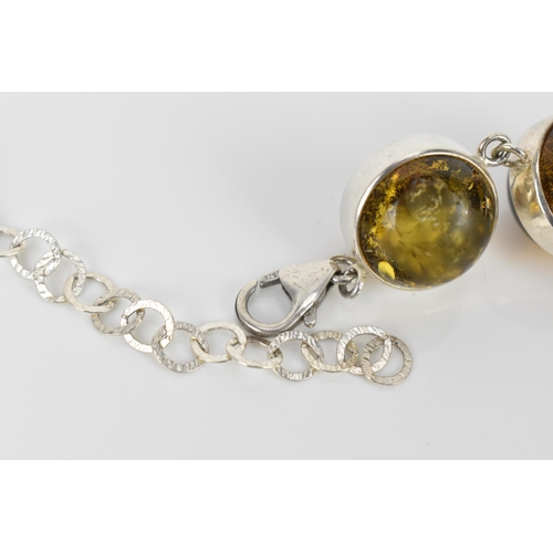 155 - A silver and green amber bead necklace with matching earrings, the amber beads with silver surround,... 