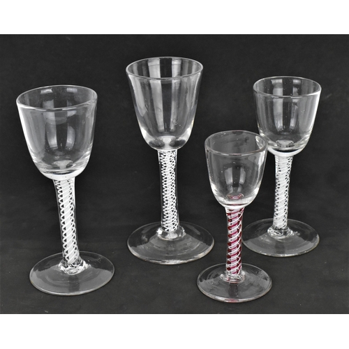 174 - A group of four Georgian wine glasses, each with ogee bowl, on air twist stems, one with red twist, ... 