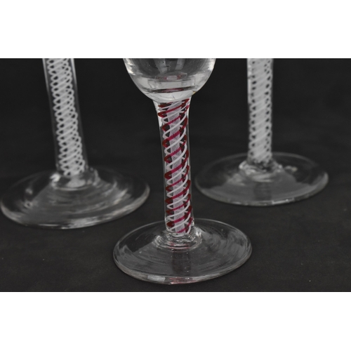 174 - A group of four Georgian wine glasses, each with ogee bowl, on air twist stems, one with red twist, ... 