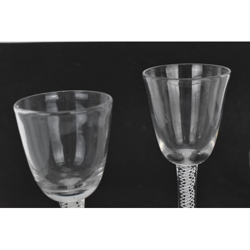 174 - A group of four Georgian wine glasses, each with ogee bowl, on air twist stems, one with red twist, ... 