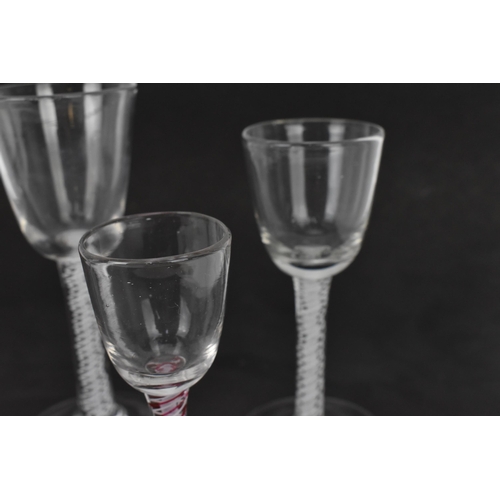 174 - A group of four Georgian wine glasses, each with ogee bowl, on air twist stems, one with red twist, ... 