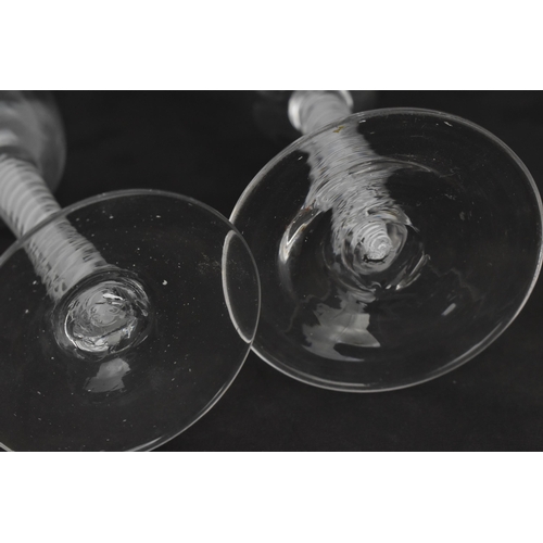 174 - A group of four Georgian wine glasses, each with ogee bowl, on air twist stems, one with red twist, ... 