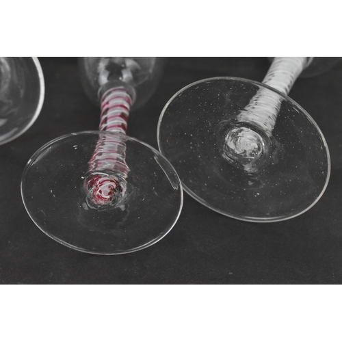 174 - A group of four Georgian wine glasses, each with ogee bowl, on air twist stems, one with red twist, ... 