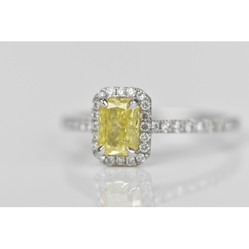 181 - A fancy intense yellow diamond and diamond cluster ring, the cut corner rectangular modern brilliant... 