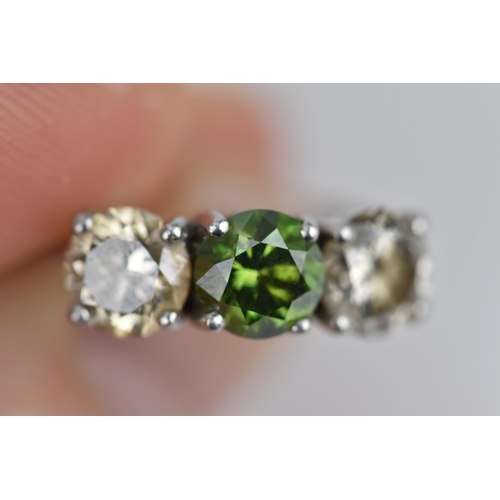 189 - A three stone platinum and diamond ring, with central green diamond, flanked by two similar sized br... 