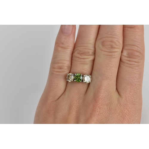 189 - A three stone platinum and diamond ring, with central green diamond, flanked by two similar sized br... 