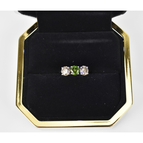 189 - A three stone platinum and diamond ring, with central green diamond, flanked by two similar sized br... 