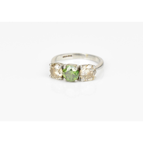 189 - A three stone platinum and diamond ring, with central green diamond, flanked by two similar sized br... 