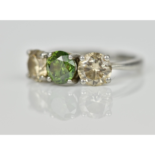 189 - A three stone platinum and diamond ring, with central green diamond, flanked by two similar sized br... 