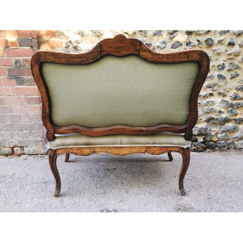 162 - A Louis XV style carved walnut framed sofa, with fleur de lys pattern upholstery, the cartouche back... 