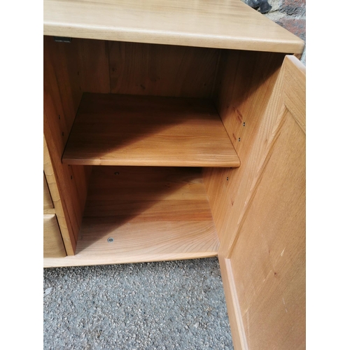 57 - An Ercol 455 light elm sideboard, of rectangular form with central top cutlery drawer above two othe... 