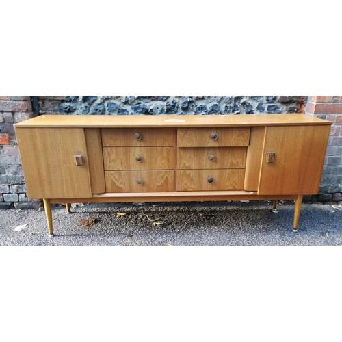 68 - A 1970s design light teak sideboard, with six drawers to the centre flanked by a cupboard door eithe... 