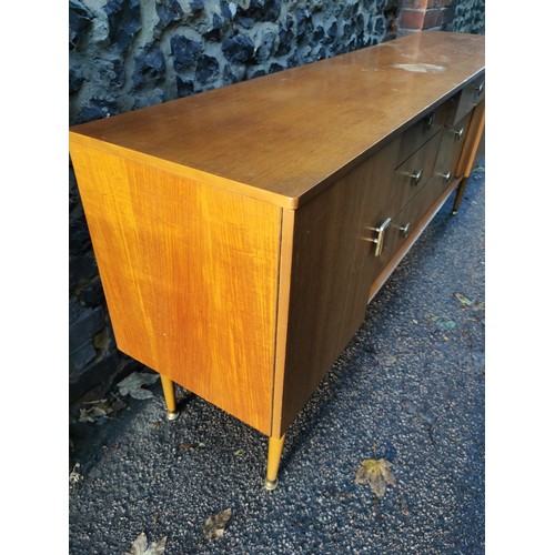 68 - A 1970s design light teak sideboard, with six drawers to the centre flanked by a cupboard door eithe... 