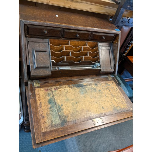 414 - An early 20th century oak bureau having a fall flap opening to reveal a slide out fitted interior an... 