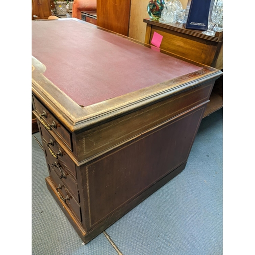 165 - A late 19th/early 20th century mahogany, twin pedestal desk having a red leather topped scriber, inl... 