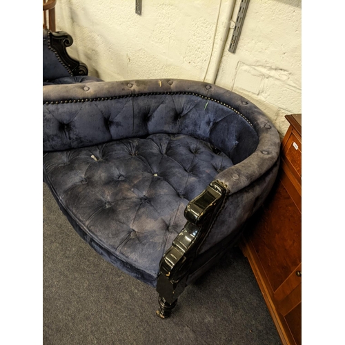 404 - A late 20th century love seat with a black gloss finished frame, button upholstered in blue velvet f... 