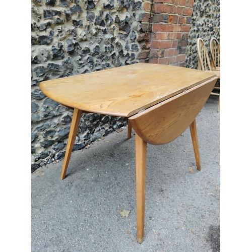 60 - A mid century blonde elm circular drop leaf table together with a set of six Ercol windsor dining ch... 