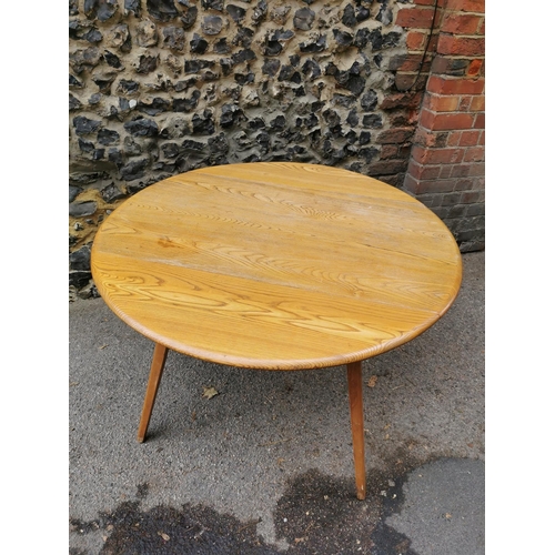 60 - A mid century blonde elm circular drop leaf table together with a set of six Ercol windsor dining ch... 