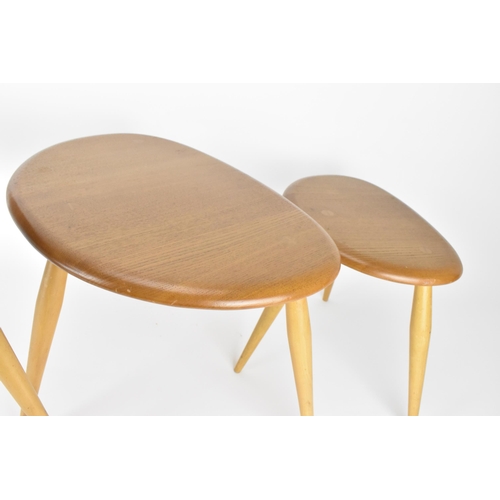 62 - A nest of three Ercol blonde elm pebble tables, model 354, each raised on three turned splayed legs,... 