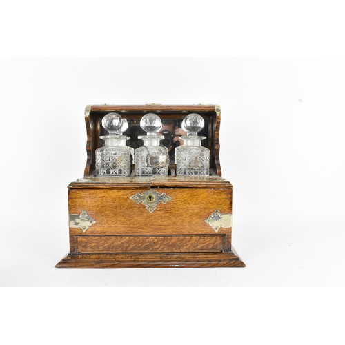 296 - A Victorian white metal mounted oak tantalus, containing three cut glass decanters, with hallmarked ... 