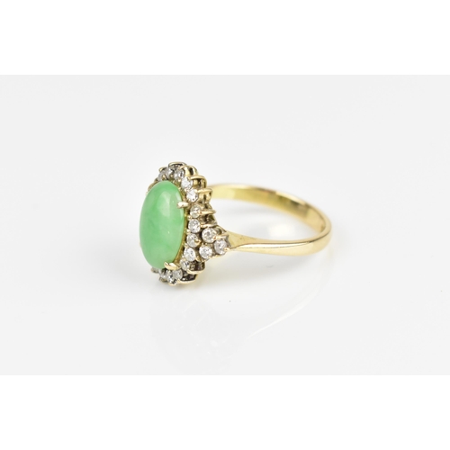 141 - A 14ct yellow gold, diamond and green jade dress ring, with central oval cabochon jade in a halo of ... 