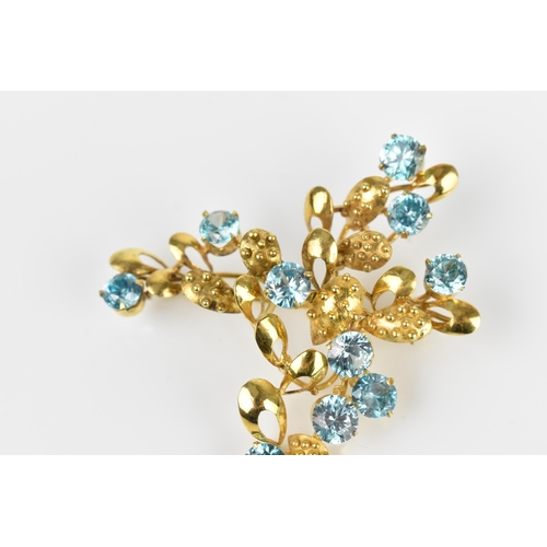 147 - A 9ct yellow gold and blue stone floral brooch, modelled as a spray of foliage inset with round cut ... 