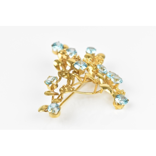 147 - A 9ct yellow gold and blue stone floral brooch, modelled as a spray of foliage inset with round cut ... 