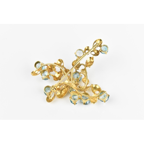 147 - A 9ct yellow gold and blue stone floral brooch, modelled as a spray of foliage inset with round cut ... 