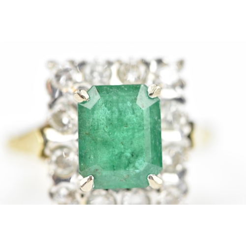 153 - An 18ct yellow gold, emerald and diamond dress ring, with central step cut emerald in a halo of twel... 