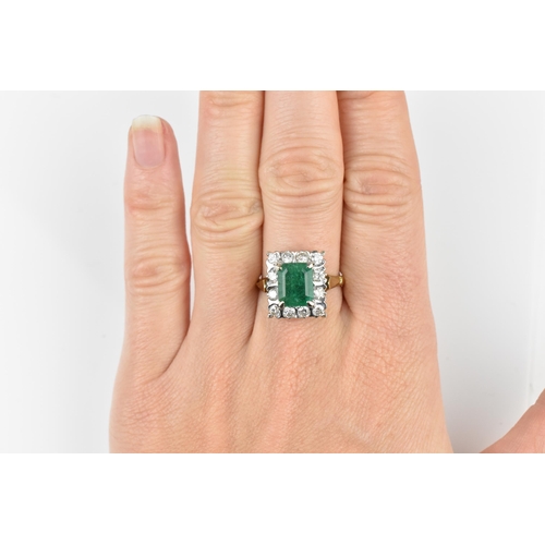 153 - An 18ct yellow gold, emerald and diamond dress ring, with central step cut emerald in a halo of twel... 